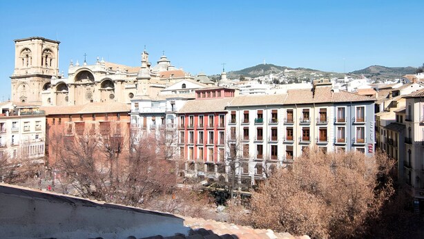 A cityscape with historic architecture, including a prominent church with a bell tower, and modern buildings with balconies.