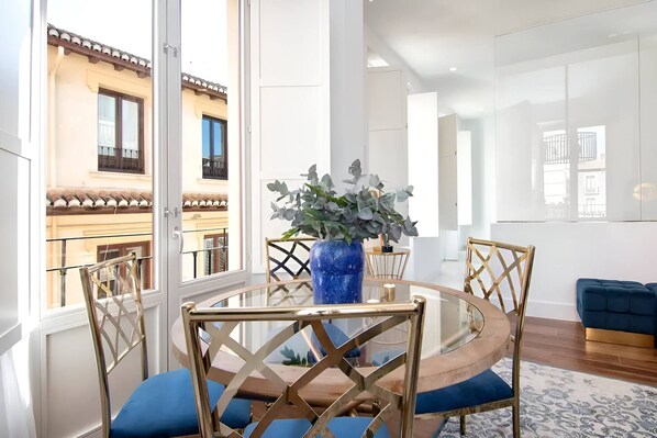 A modern dining area with a round table, chairs, and a blue vase with plants.