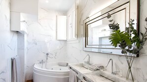 A modern bathroom with a freestanding bathtub, a large mirror, and a marble countertop.