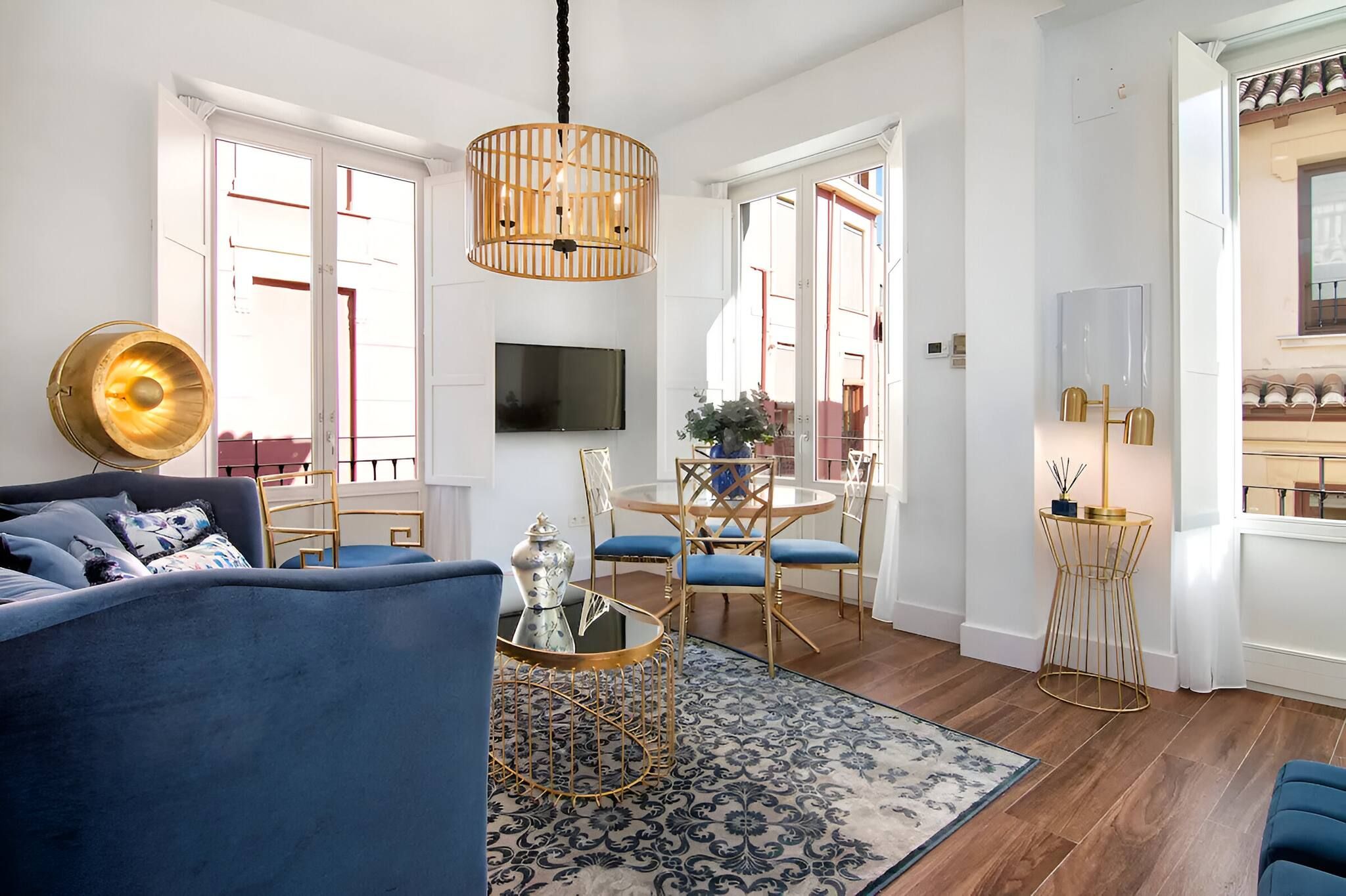 Uma sala de estar moderna com um sofá azul, uma mesa de centro redonda e um lustre.