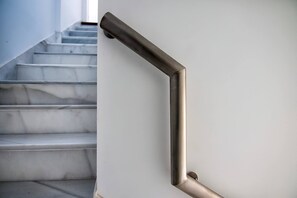 A staircase with a metallic handrail and marble steps.