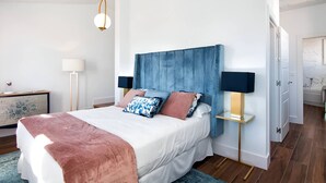 A modern bedroom with a large bed, bedside lamps, and a view of the bathroom.