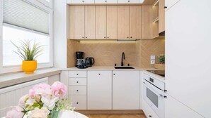A modern kitchen with white cabinets, a black faucet, and a built-in oven. - Spacious Apartment | 2 Bedrooms | In the Heart of Kazimierz. (Kraków)