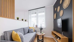 A modern living room with a grey sofa, wooden floor, and a black wall with decorative items. - Spacious Apartment | 2 Bedrooms | In the Heart of Kazimierz. (Kraków)