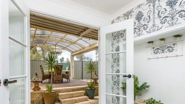 Une véranda avec un toit en verre, un espace patio avec des meubles d’extérieur et des plantes en pot.