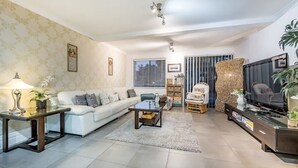 Un salon moderne avec un canapé blanc, une table basse, un meuble pour la télévision et un fauteuil décoratif.