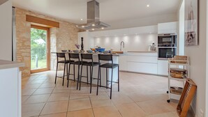 A modern kitchen with a central island, bar stools, a built-in oven, and a large window.