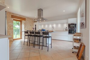 A modern kitchen with a central island, bar stools, a built-in oven, and a large window.