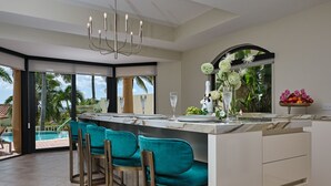 Une cuisine moderne dotée d’un grand îlot central, de tabourets de bar et offrant une vue sur une piscine.