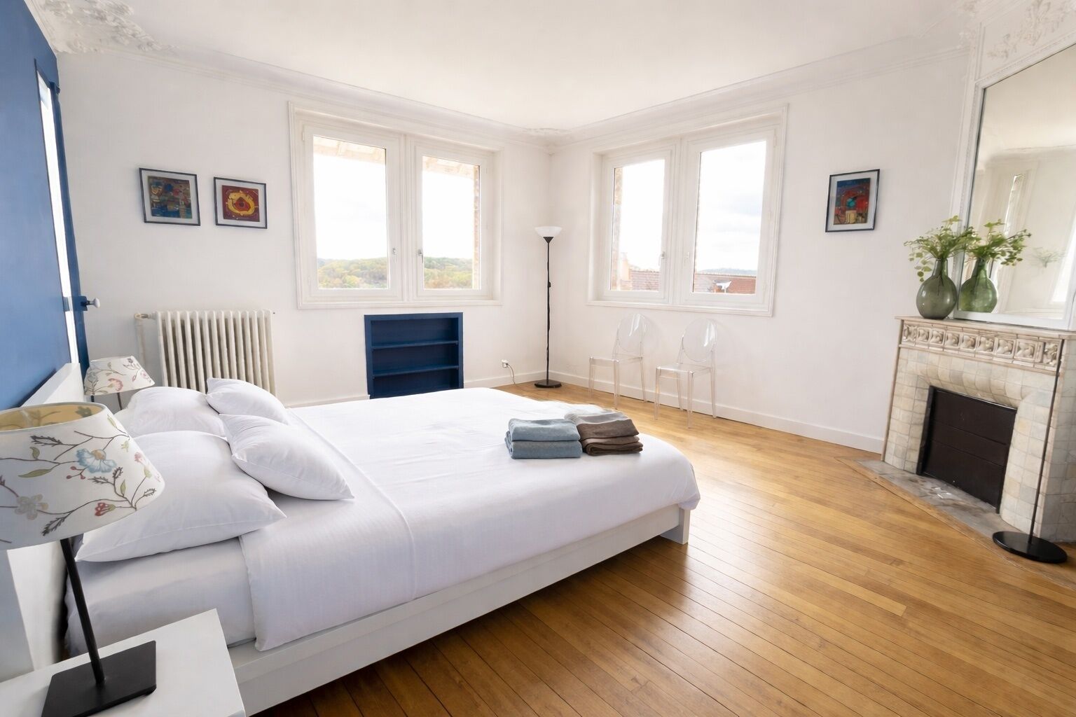 Une chambre à coucher avec un lit, un radiateur, une cheminée et deux fenêtres.