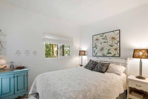 Une chambre à coucher comprenant un lit, une fenêtre, une table de chevet, une lampe et un élément décoratif mural.