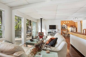 A modern living room with a fireplace, a sofa, a coffee table, and a view of the outdoors.