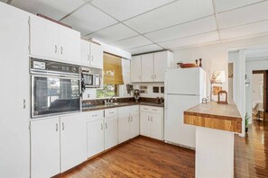 Une cuisine avec des meubles blancs, un four à micro-ondes, une cuisinière et un réfrigérateur.