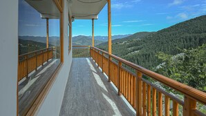Un balcon doté d’une balustrade en bois, d’où l’on peut admirer un paysage montagneux.