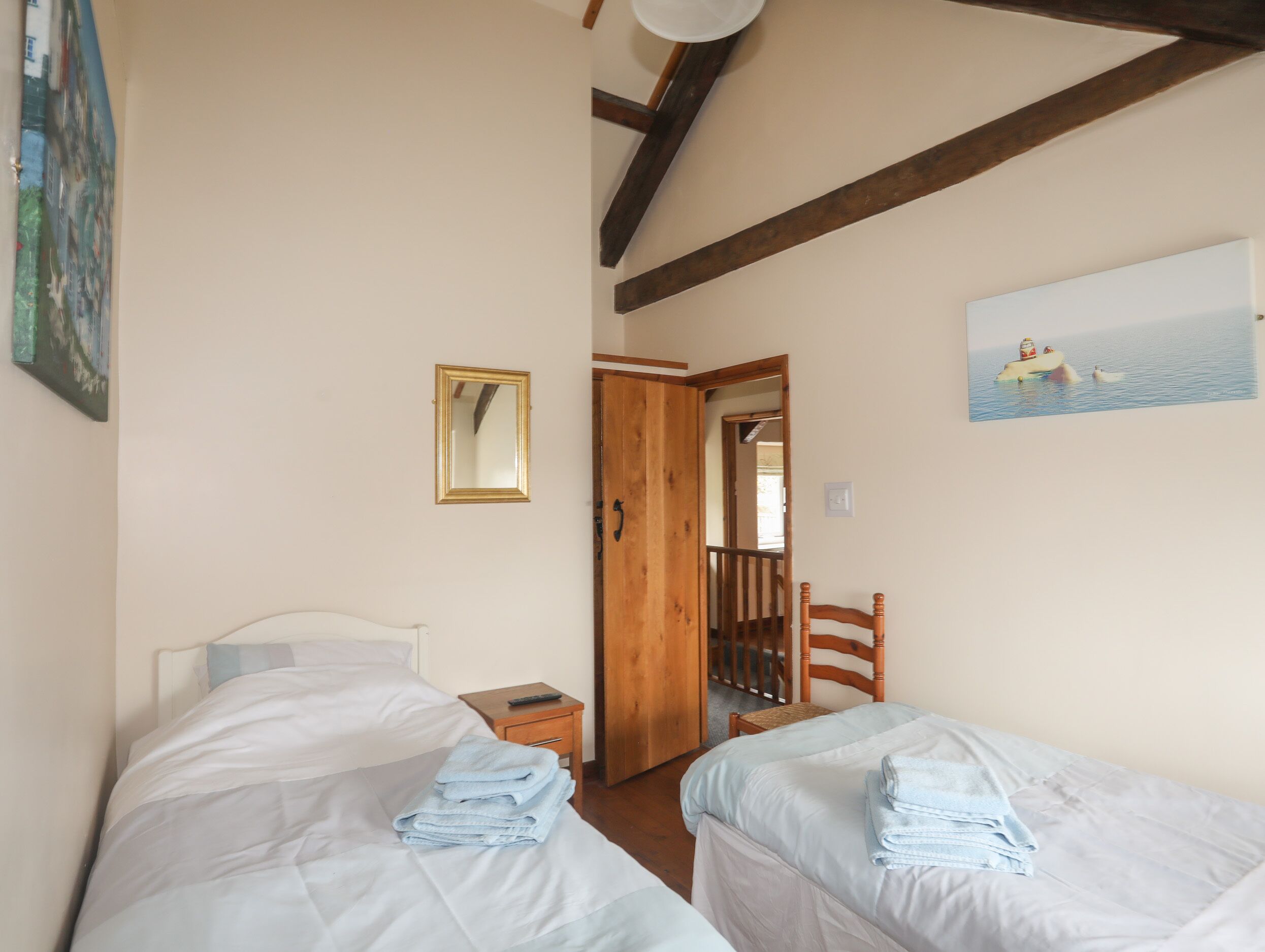 Ein Schlafzimmer mit zwei Betten, einer Holztür, einem Sessel und einem Bild an der Wand.