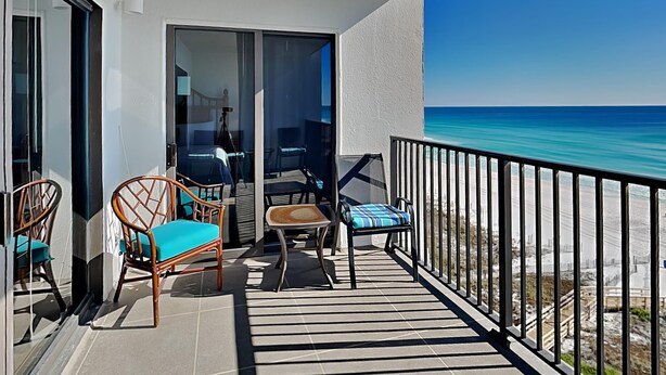 Ein Balkon mit Blick auf den Ozean, ausgestattet mit Stühlen und einem Tisch.