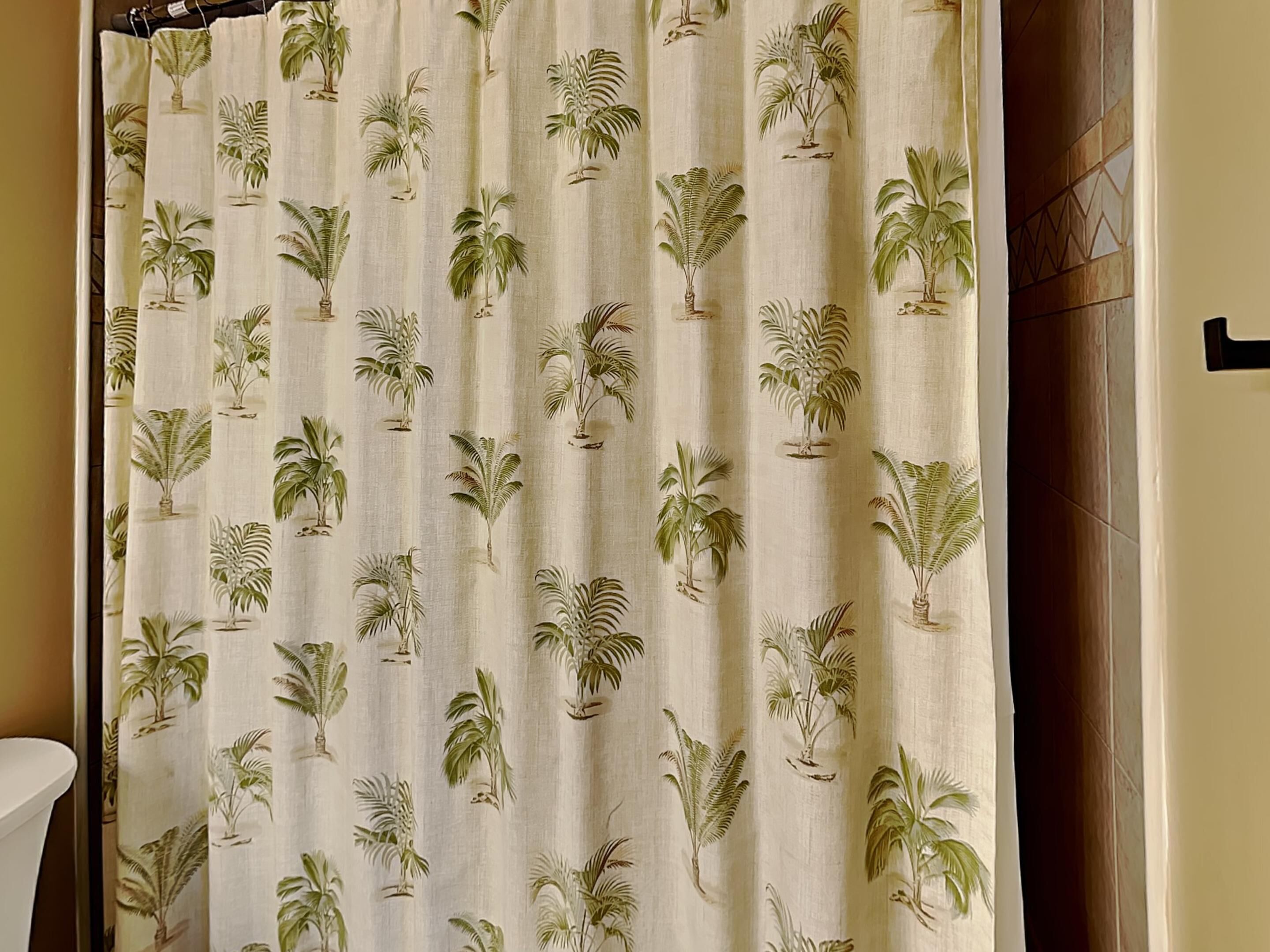 A bathroom with a shower curtain featuring a tropical plant pattern.