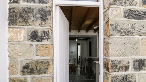 A stone-walled interior with a doorway leading to a bar area.