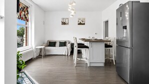 Una cocina moderna con refrigerador, mesa y sillas.