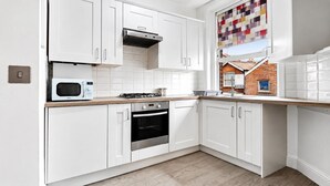 Una cocina moderna con armarios blancos, microondas, estufa, horno y una ventana con vistas coloridas.