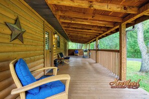 Relax on the covered porch with wicker chairs and enjoy the surrounding greenery.