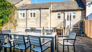 A stone house with a tiled roof, a staircase, and a patio with a table and chairs. - Polly's Folly (Swanage)