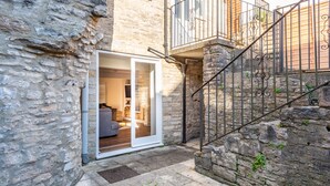 A stone building with a wooden balcony and a metal staircase. - Polly's Folly (Swanage)