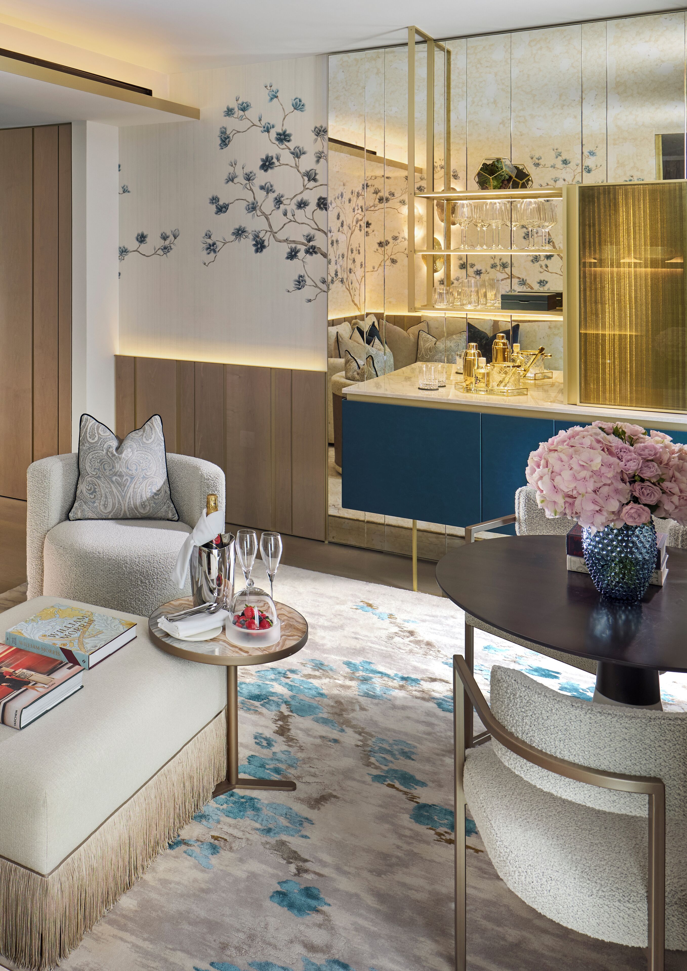 A modern living room with a sofa, a coffee table with a vase of flowers, and a dining area with a table and chairs.