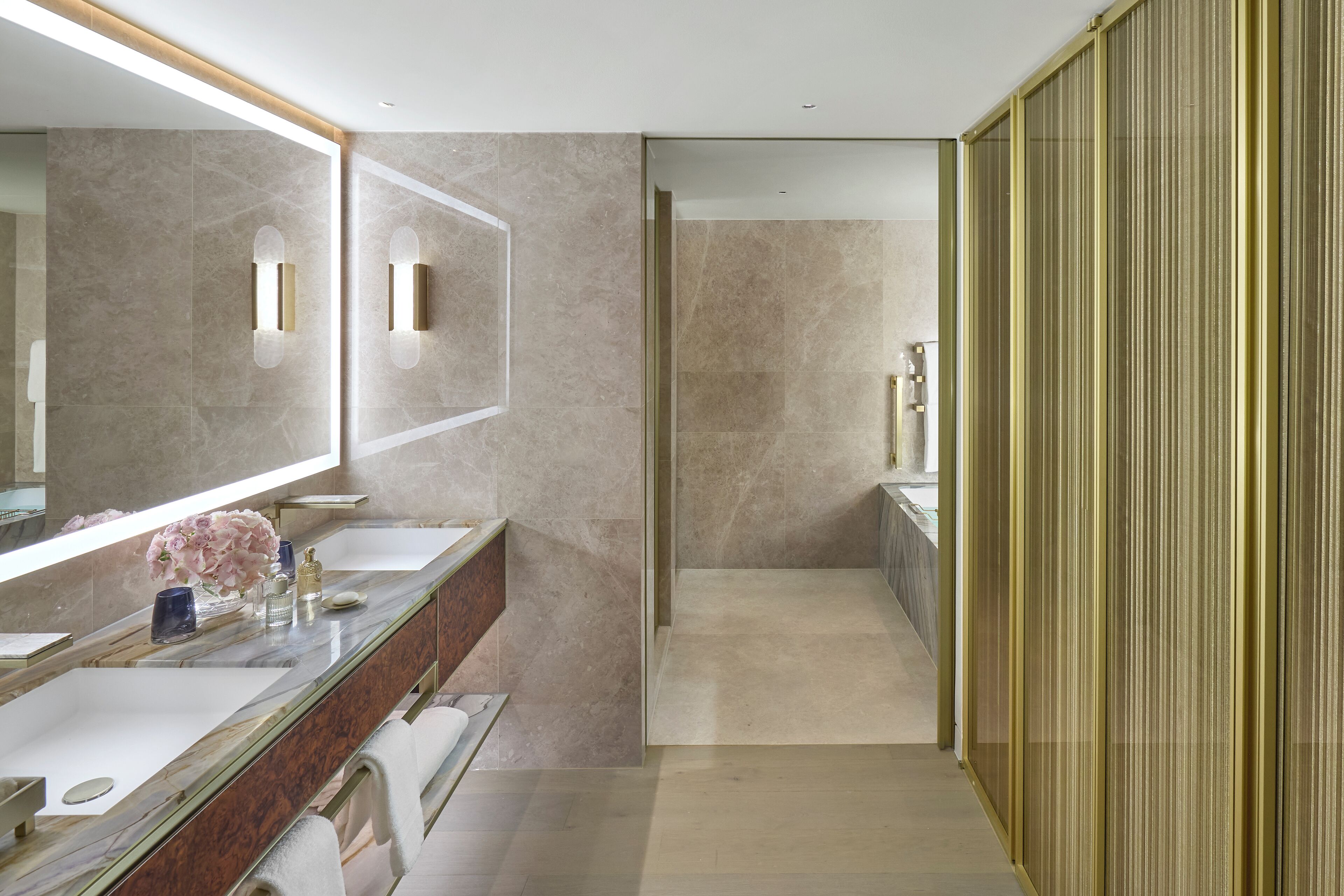 A modern bathroom with a large mirror, two sinks, a shower area, and a walk-in closet with sliding doors.