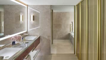A modern bathroom with a large mirror, two sinks, a shower area, and a walk-in closet with sliding doors.