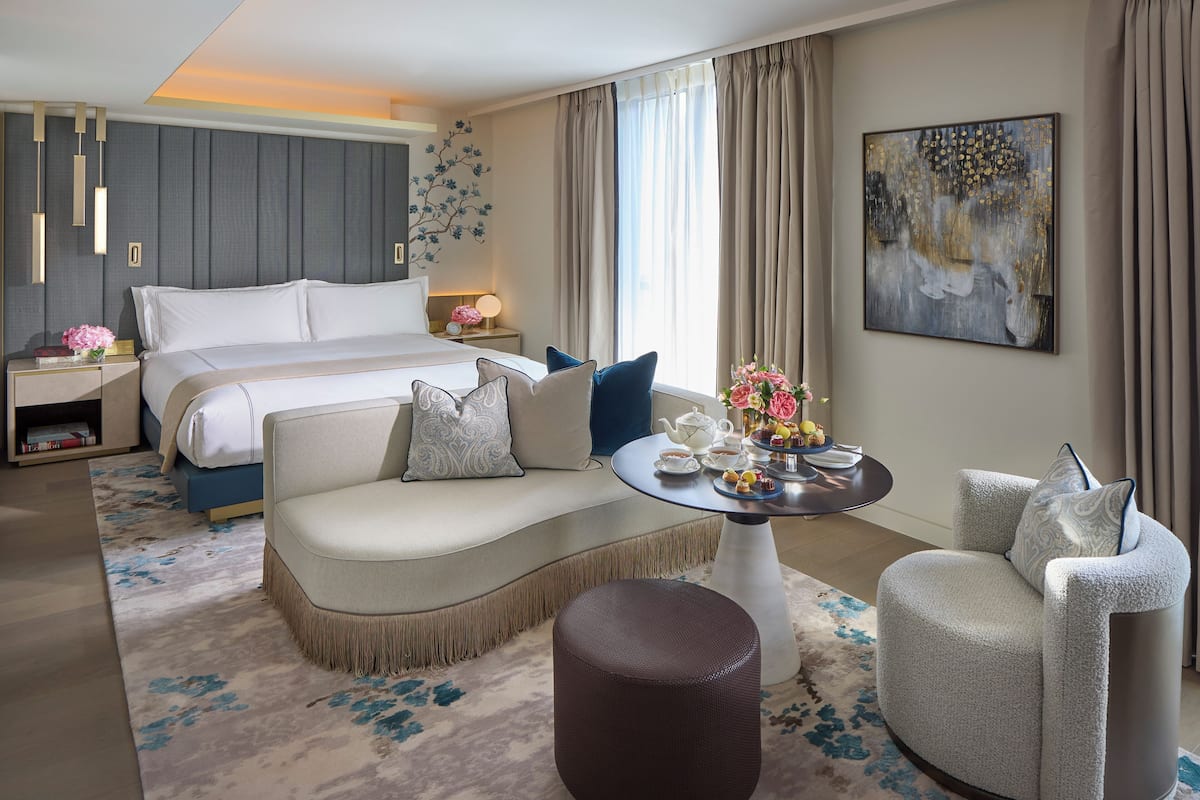 Una habitación de hotel moderna con una cama grande, un sofá, una mesa de centro redonda y una silla.
