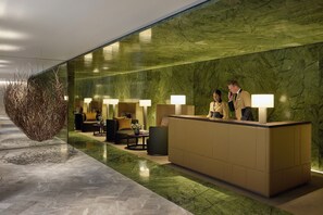 A reception area with a marble reception desk, seating with lamps, and a decorative plant. - Mandarin Oriental Mayfair, London (London)
