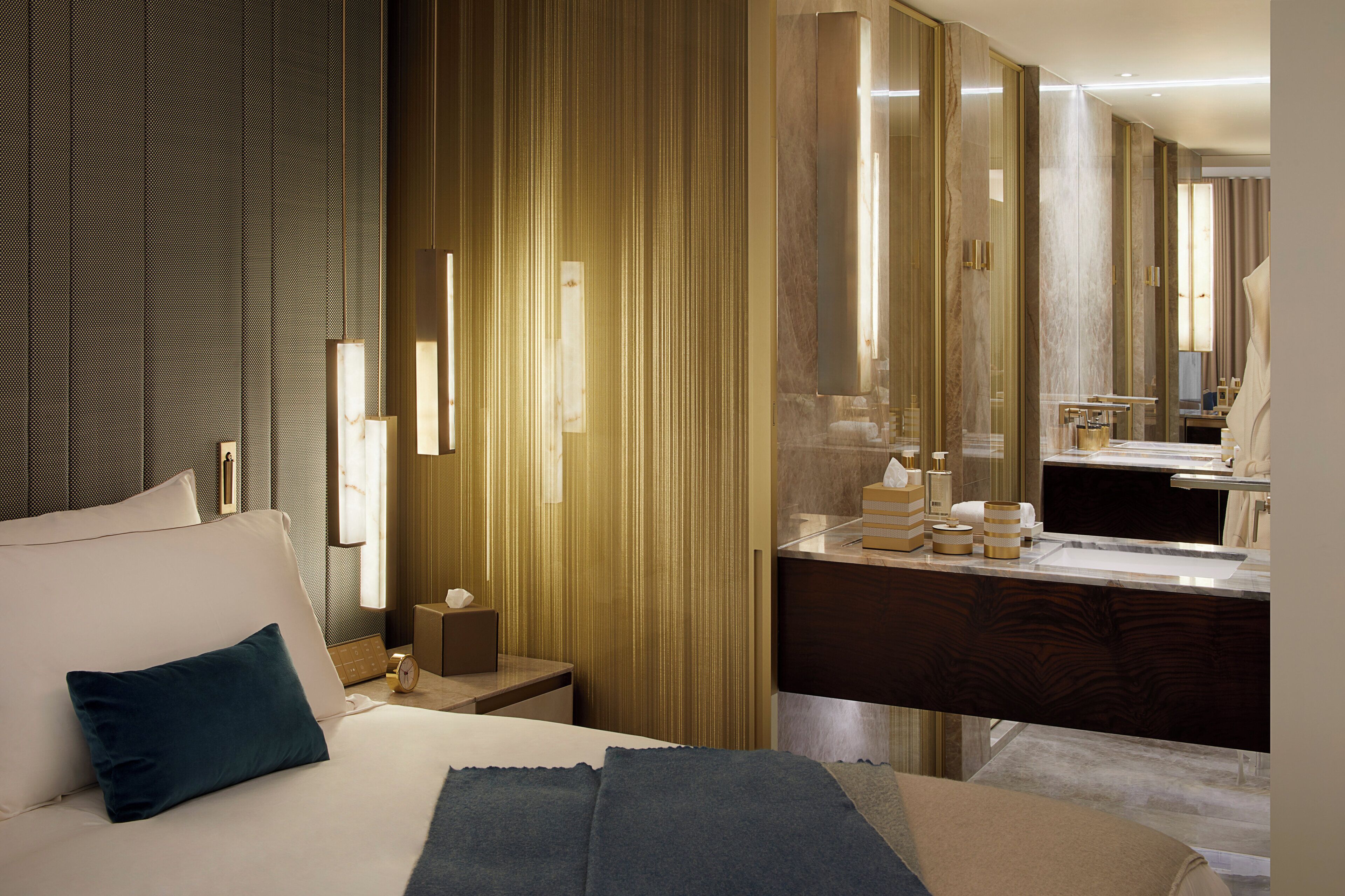 Una habitación de hotel con cama, mesita de noche y un espejo grande.