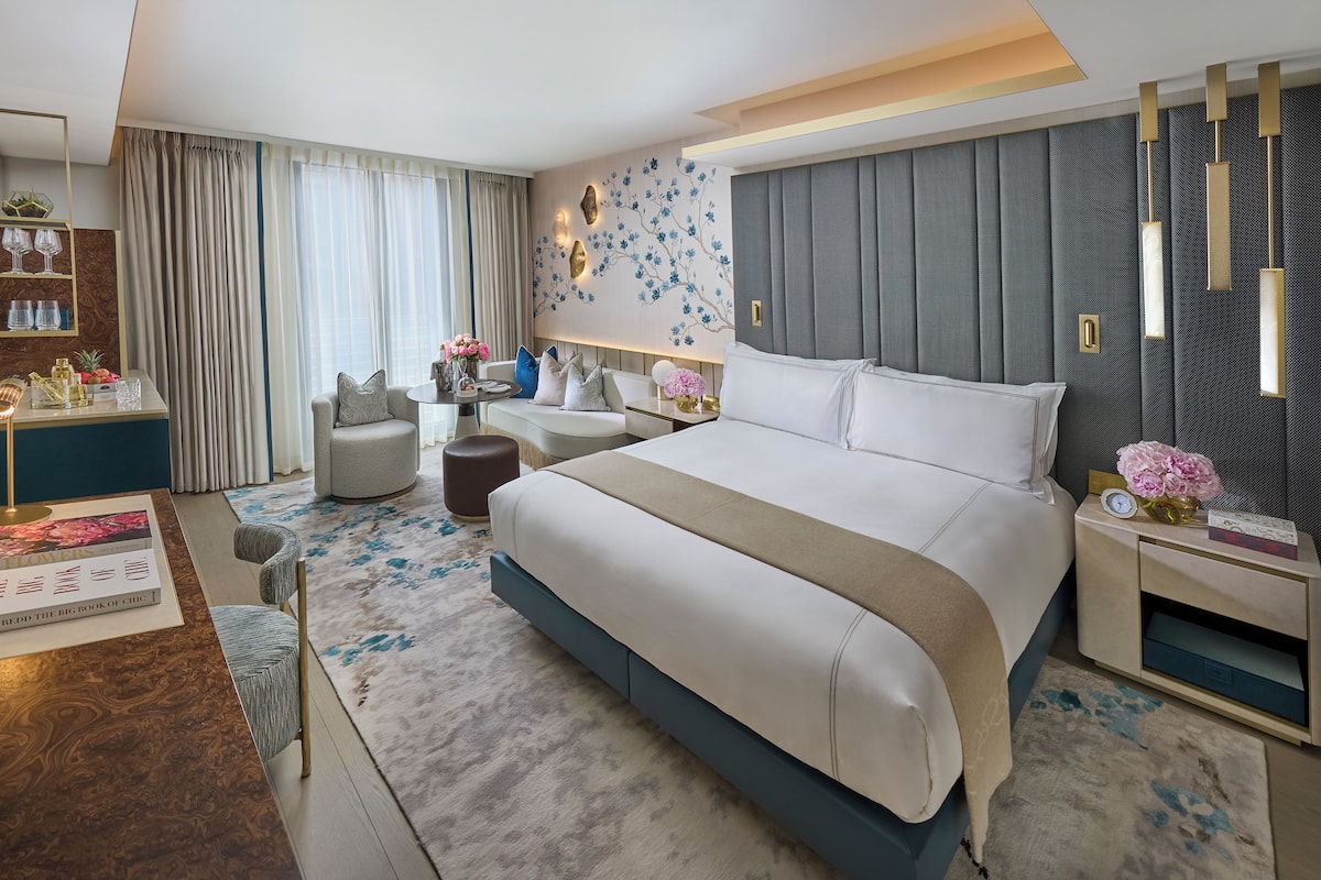 Una habitación de hotel moderna con una cama grande, un escritorio con silla, un sofá y un comedor.