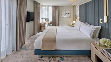 A modern hotel room with a large bed, a desk, a vanity, and a large window with curtains.