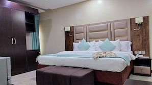 Ein Hotelzimmer mit einem großen Bett, einem Kleiderschrank, einem Nachttisch und einem kleinen Schreibtisch.