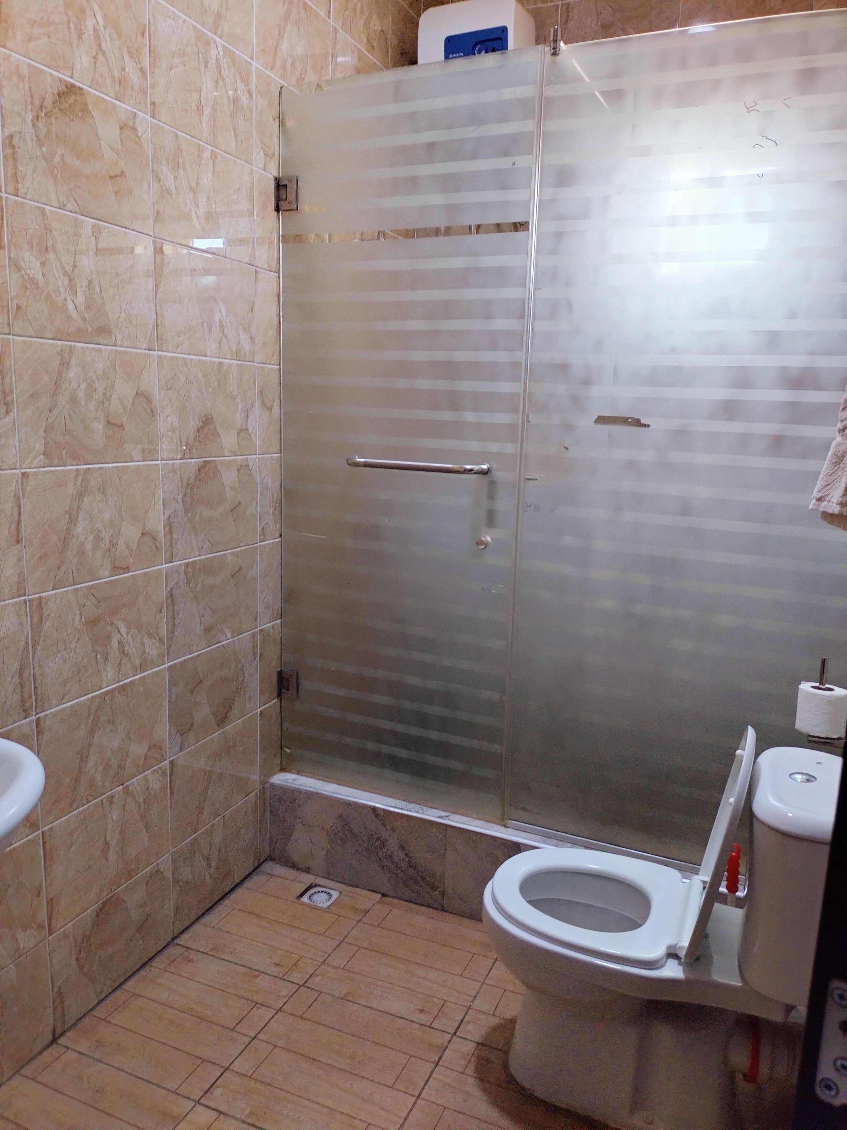 A bathroom with a glass-enclosed shower, a toilet, and a hand dryer.