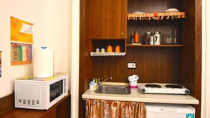 A compact kitchenette with a microwave, sink, and small refrigerator. - Sunrise Studio Apartment (Napoli)