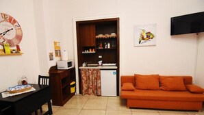 A compact living space with a kitchenette, a dining table, and a sofa. - Sunrise Studio Apartment (Napoli)