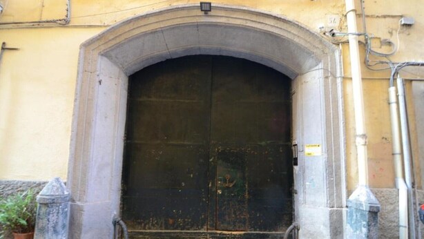 A large, dark, arched entrance to a building with a metal door. - Sunrise Studio Apartment (Napoli)