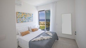 A modern bedroom with a large bed, a view of the sea, and a painting on the wall. - Villa Roxy, Fantastic 3BDR Seafront Protaras Villa with Pool (Protaras)