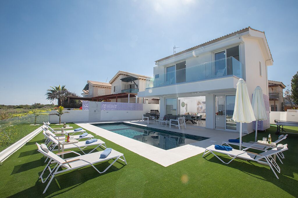 A modern two-story house with a swimming pool, outdoor seating, and a well-maintained lawn.