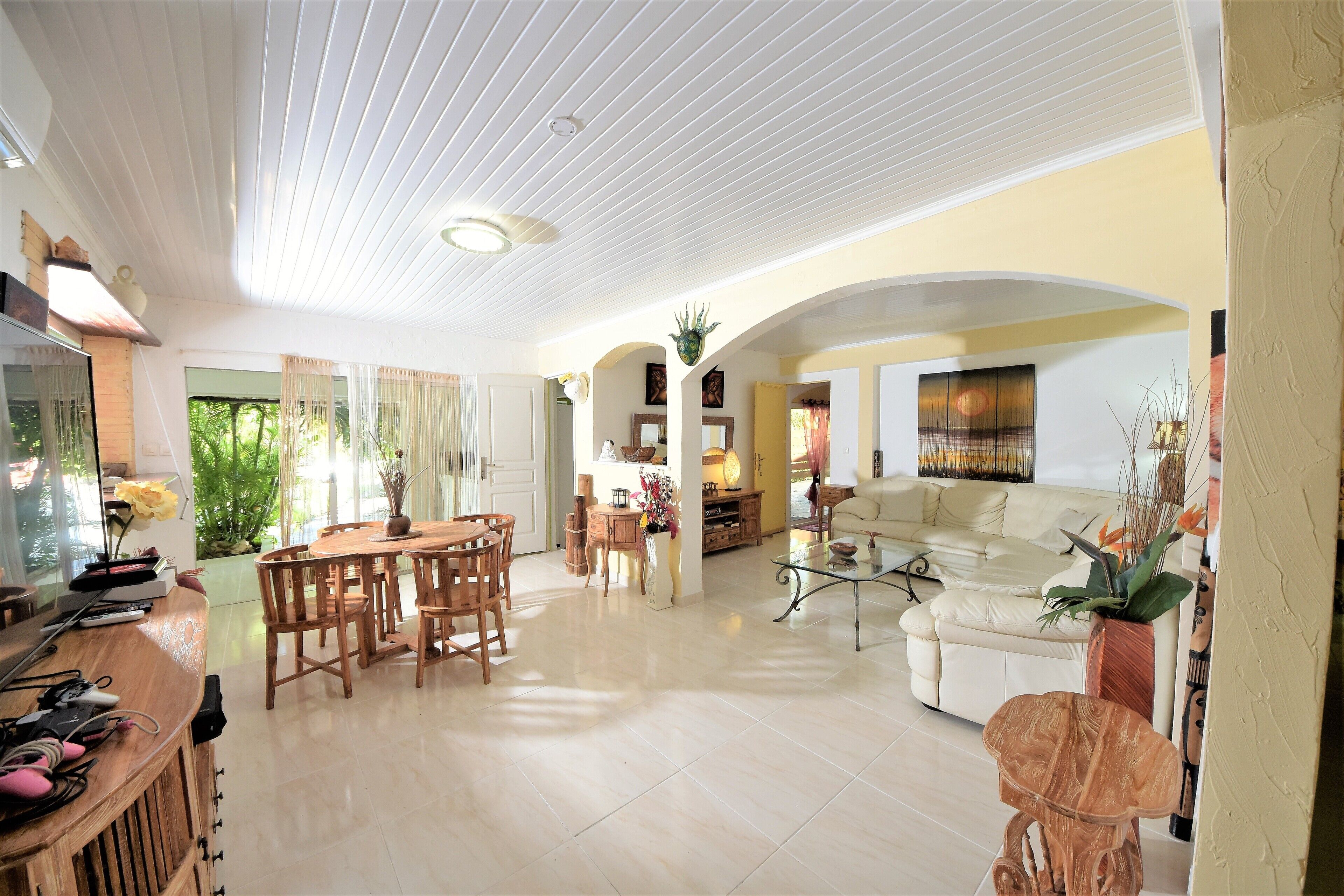 A spacious living area with a dining table, sofas, and a TV.