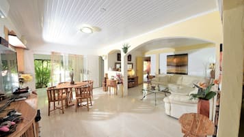A spacious living area with a dining table, sofas, and a TV.