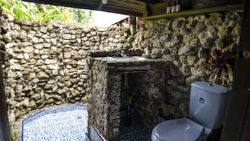 Bathroom features a toilet, sink with stone countertop, and a small rug.