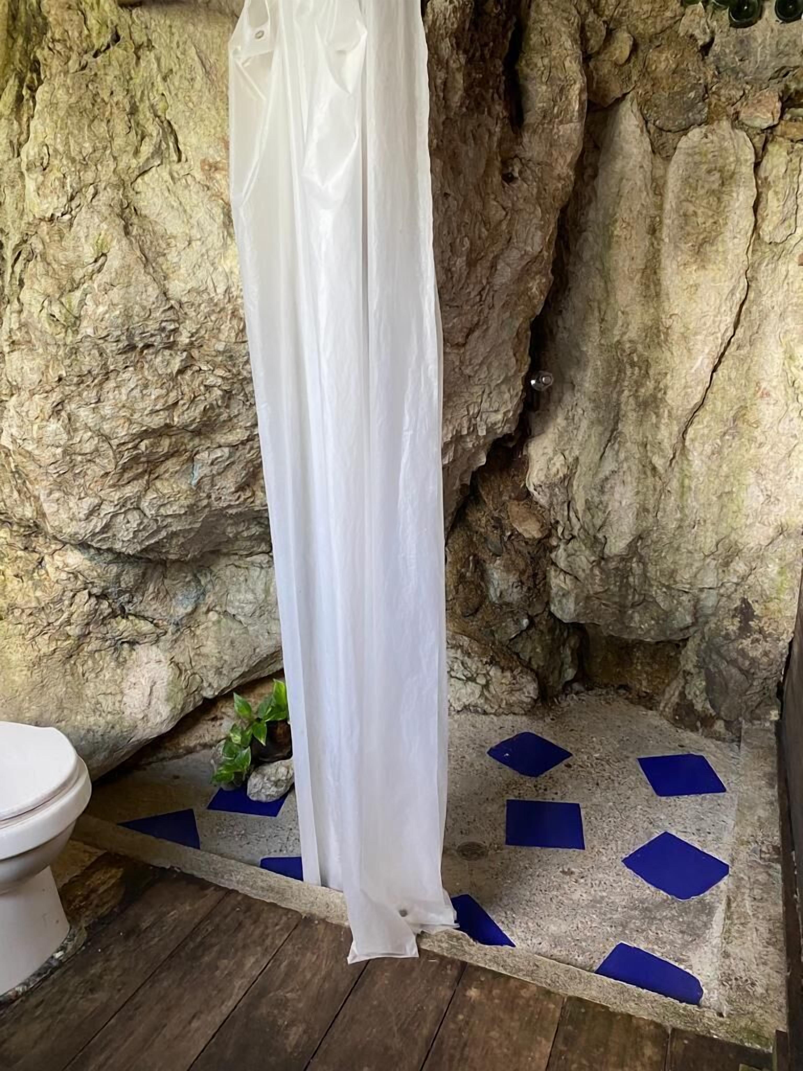 A bathroom with a white shower curtain, a toilet, and a floor with blue tiles.