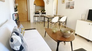 A modern living room with a sofa, dining table, and chairs. There is a kitchen visible through an archway. - Playa Paraíso apartment with lovely Mar Menor views (Playa Paraiso)