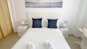 A hotel room with a bed, two pillows, two bedside tables, a lamp, and a view of the sea. - Playa Paraíso apartment with lovely Mar Menor views (Playa Paraiso)
