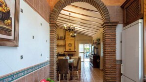 Une cuisine avec une arche en briques, un coin repas avec une table et des chaises, et un réfrigérateur.