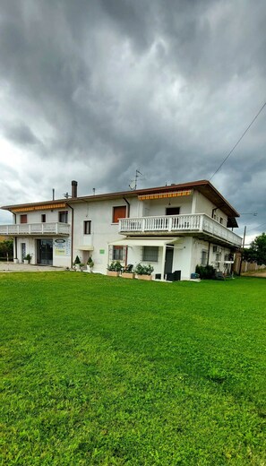 Una casa a due piani con un balcone, un portico coperto e un prato curato.